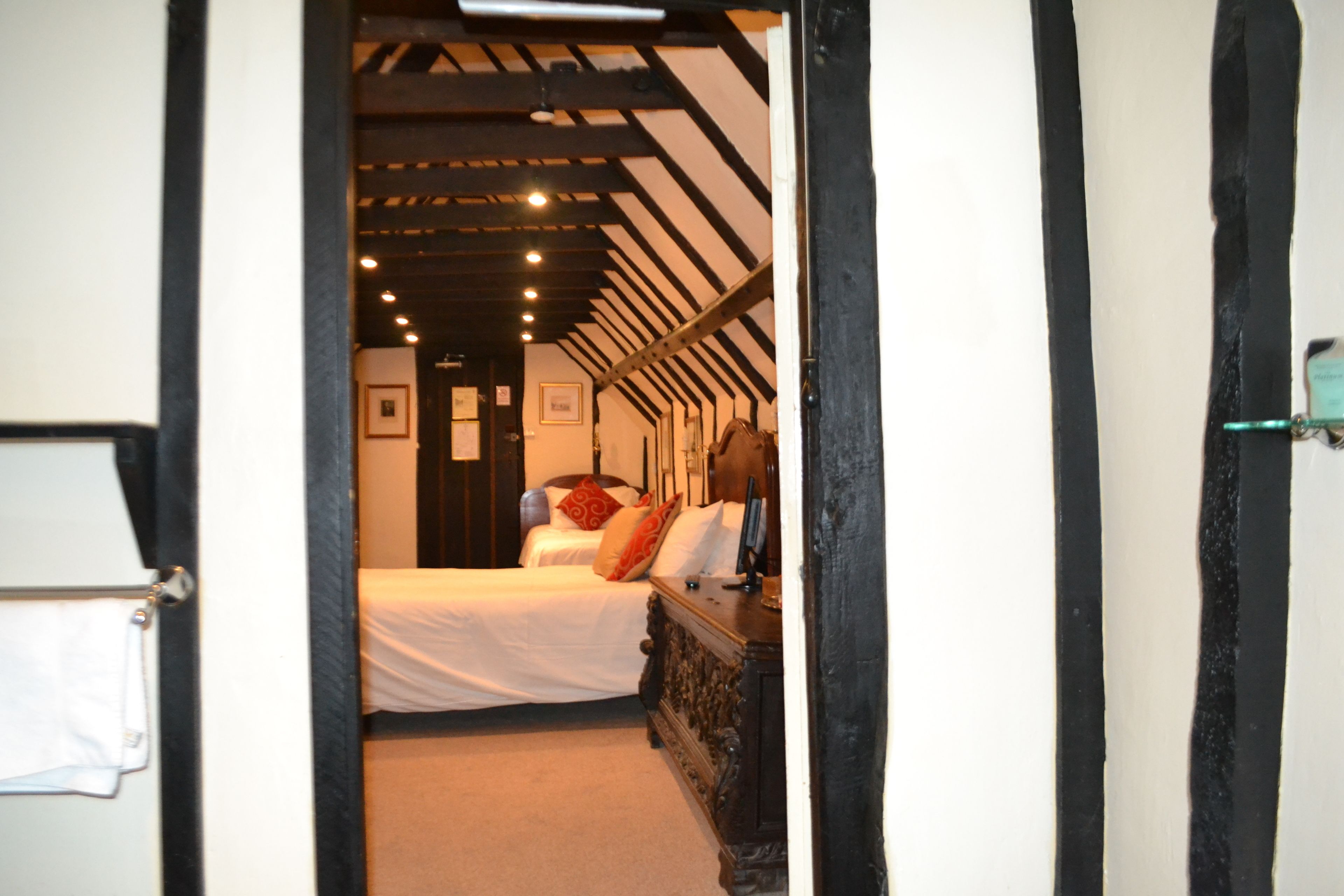Un pasillo estrecho que conduce a un dormitorio con cama, cómoda y un cuadro en la pared.
