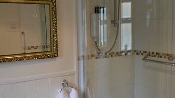 A bathroom with a white sink, a mirror with a gold frame, and a glass-enclosed shower area.