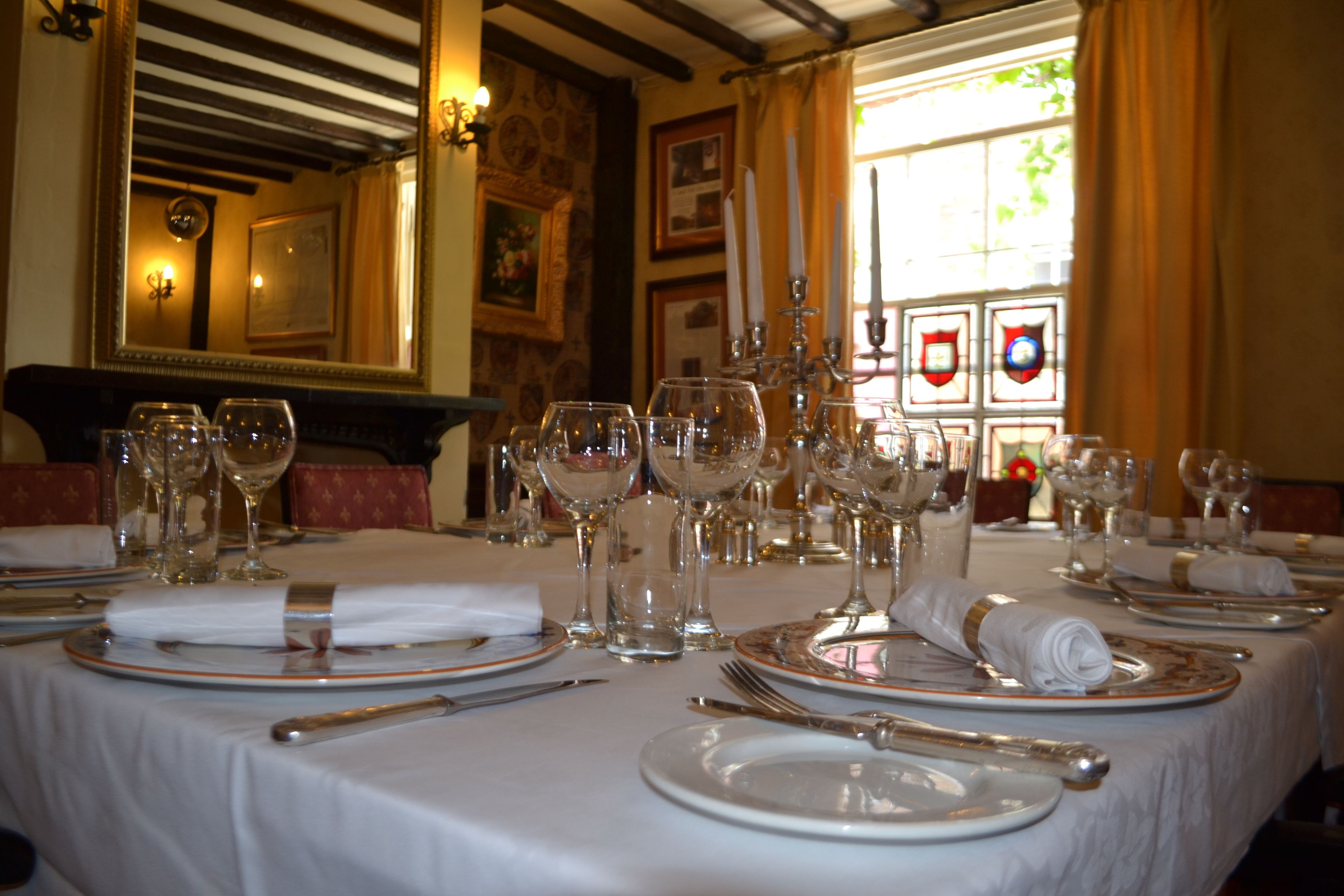 A dining table set for a meal with multiple wine glasses, plates, and cutlery.