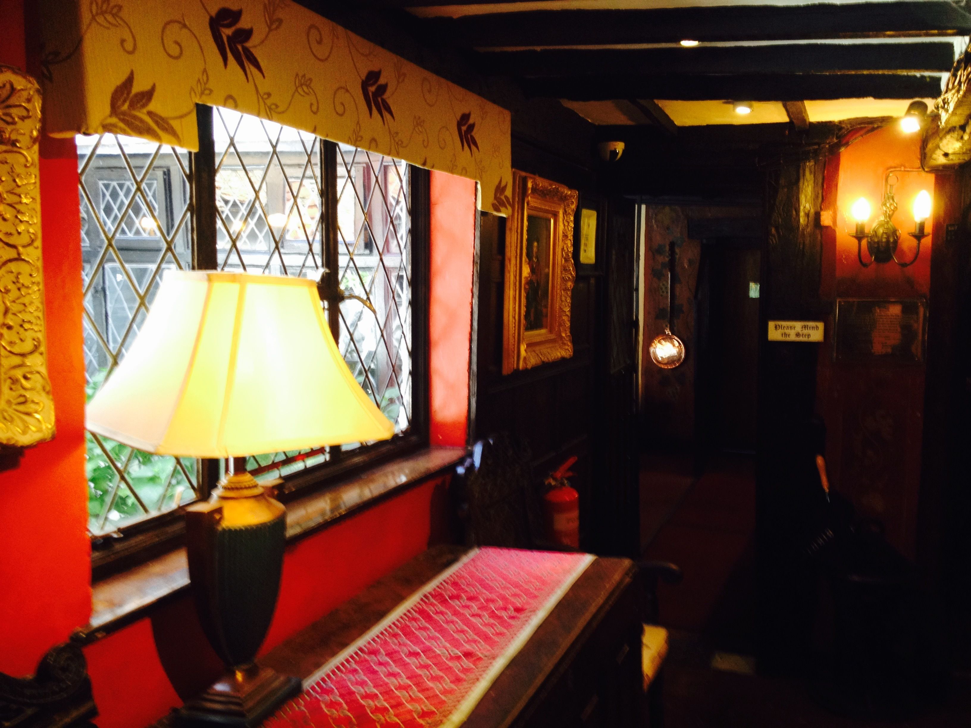 A dimly lit room with a window, a lamp, and a sign on the wall.