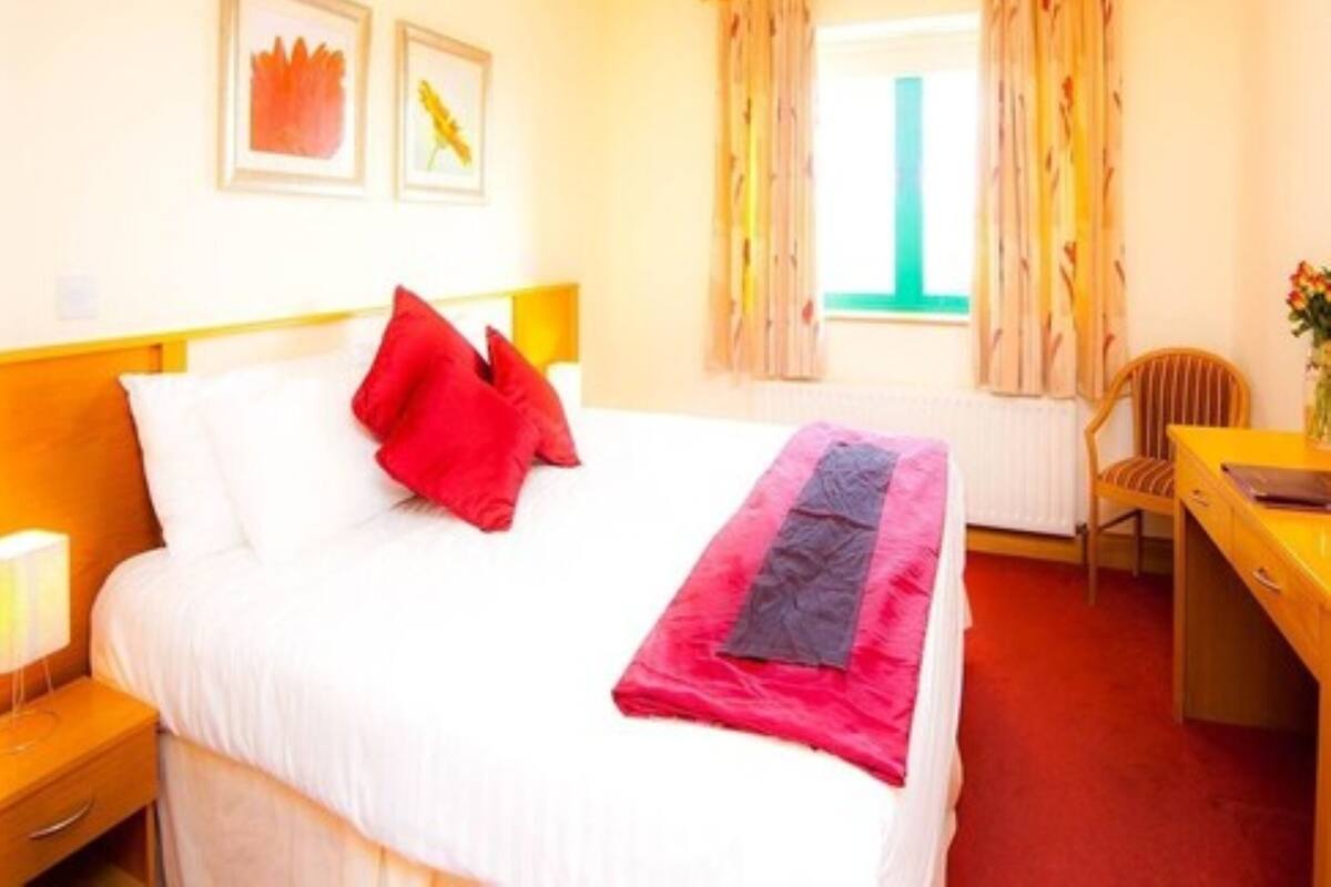 A hotel room with a bed, a desk, a chair, and a window with curtains.