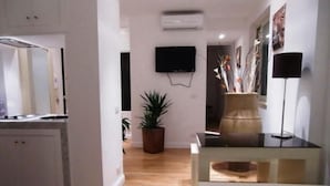 A modern kitchen with a wooden floor, a potted plant, a flat-screen TV mounted on the wall, and a vase on the table. - Casual Stay Galileo  (Reggio Calabria)