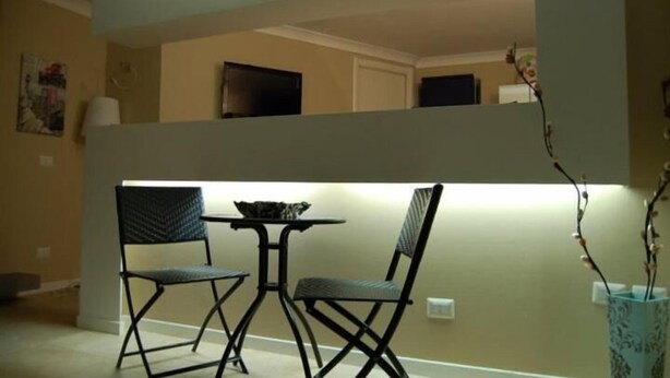 A dining area with a table and two chairs, a vase with branches, and a television on the upper level. - Casual Stay Galileo  (Reggio Calabria)