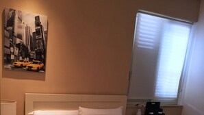 A hotel room with a large bed, a painting on the wall, a bedside table with a lamp, and a window with blinds. - Casual Stay Galileo  (Reggio Calabria)