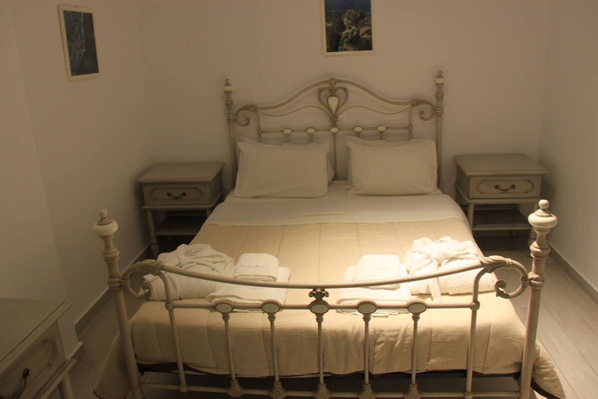 Ein Bett mit Metallgestell, zwei Nachttische und ein Wandbild.