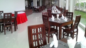 Un comedor espacioso con varias mesas y sillas, amplias ventanas que ofrecen vistas al exterior.