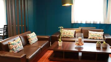 A modern living room with a brown leather sofa set, patterned cushions, a wooden coffee table, and a floor lamp.