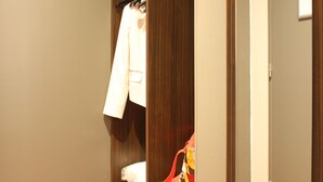 A walk-in closet with wooden shelving, a hanging rack, and a mirror. - Hôtel Orly Superior (Athis-Mons)