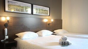 A hotel room with two beds, a wooden headboard, wall-mounted light fixtures, and framed pictures above the beds. - Hôtel Orly Superior (Athis-Mons)