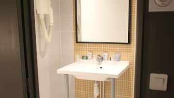 Un baño con un lavamanos blanco, un espejo y un secador de manos.