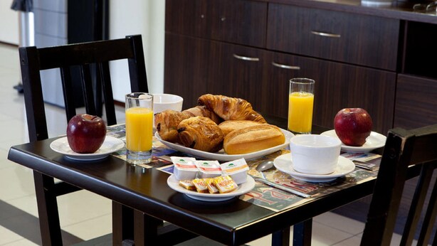 A breakfast table with croissants, apples, juice, and cereal. - Hôtel Orly Superior (Athis-Mons)