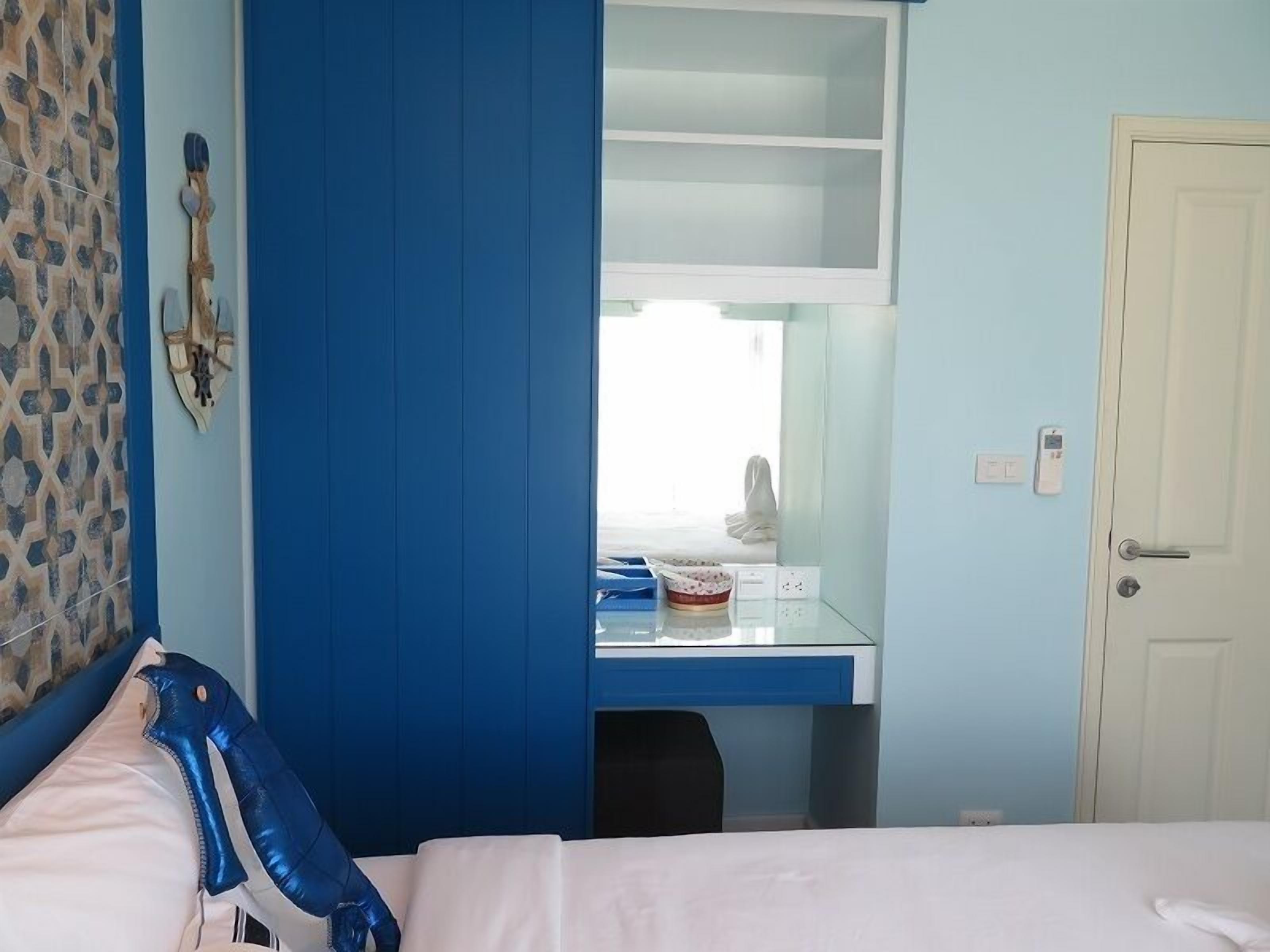 Ein Schlafzimmer mit einem Bett, einem Schreibtisch mit Stuhl, einem Kleiderschrank und einer Tür.
