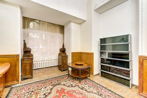 A room with a traditional wooden cabinet, a round table with a wooden top, and a patterned rug on the floor.