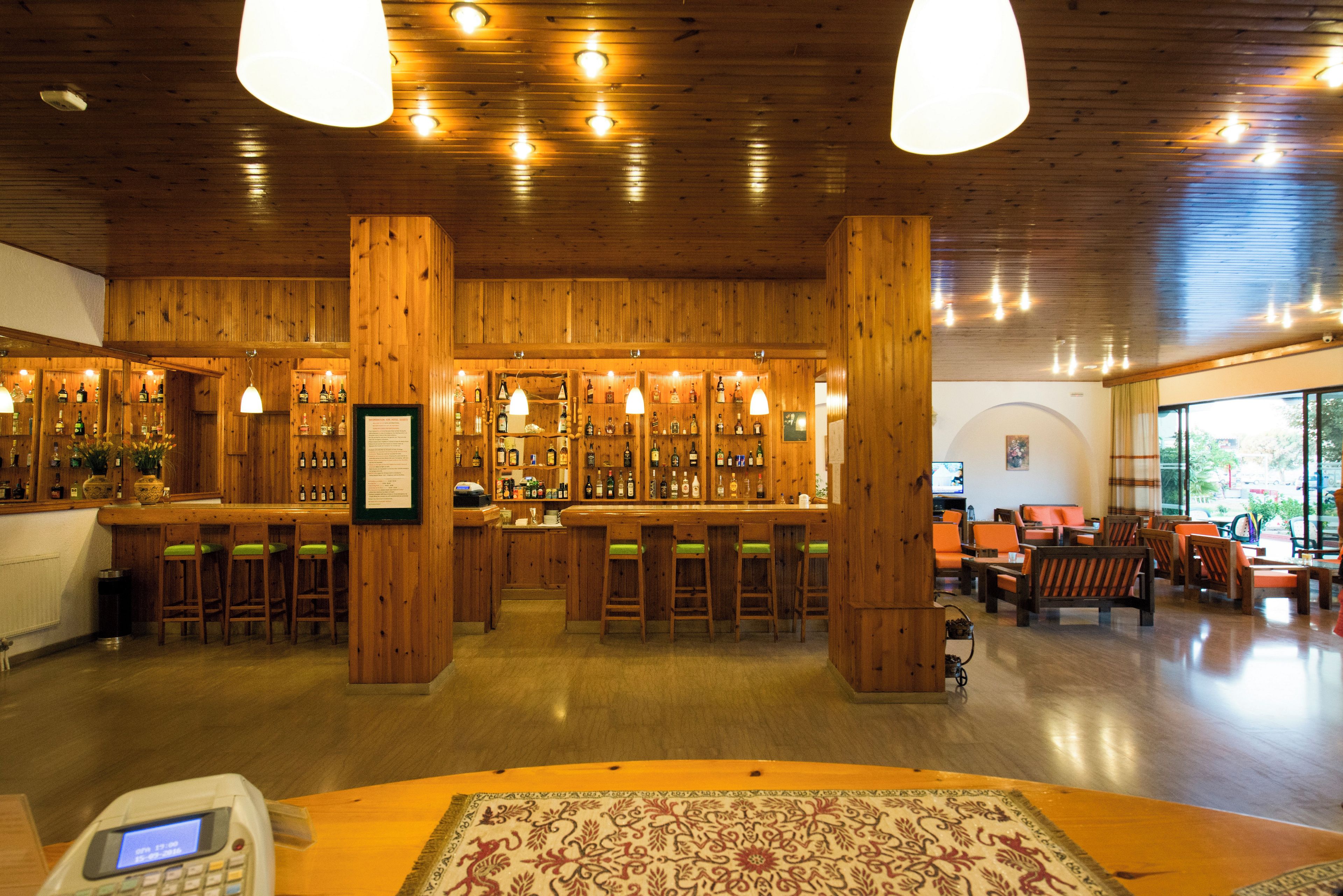Un bar aux murs en bois, avec un comptoir, entouré de chaises et de tables.