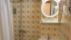 Un baño con ducha, inodoro, lavabo y espejo.