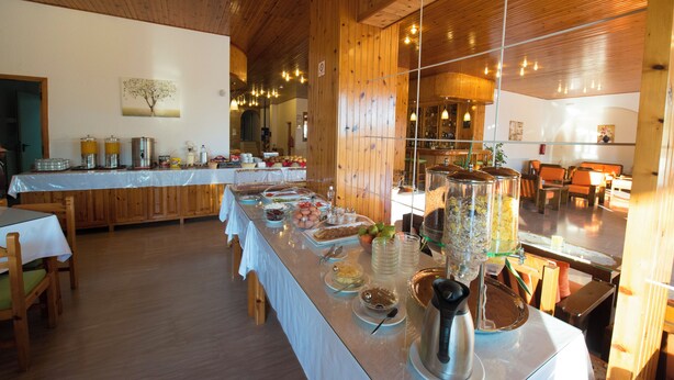 Un buffet con diversi cibi e un angolo caffè, ambientato in un interno in legno.