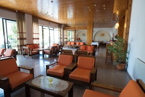 Un hall d’entrée spacieux, doté de meubles en bois, de grandes fenêtres et d’une plante en pot.