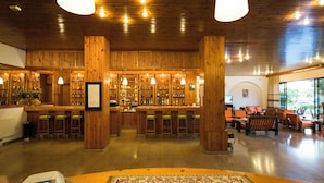 Un bar con pareti in legno e un bancone, circondato da sedie e tavoli.