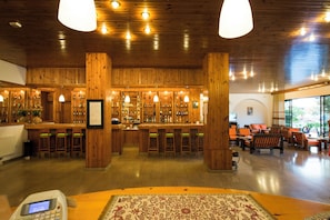 A bar with wooden walls and a counter, surrounded by chairs and tables. - International (Kos)