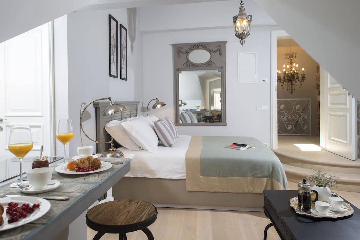 Habitación de hotel moderna con cama, mesita de noche, preparación para el desayuno y vista al comedor.