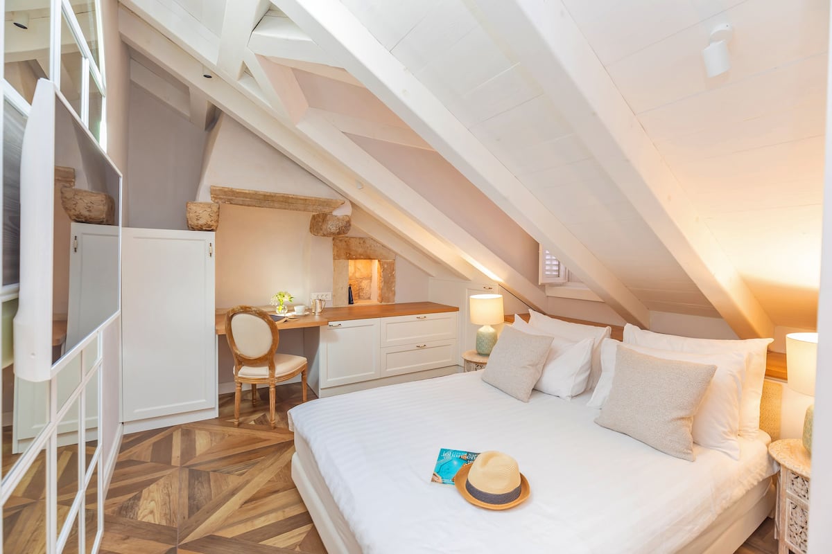 Un dormitorio en el ático con cama, escritorio y silla.