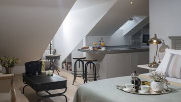 Un appartement-loft moderne et compact, comprenant une kitchenette, un coin repas et un espace salon confortable.