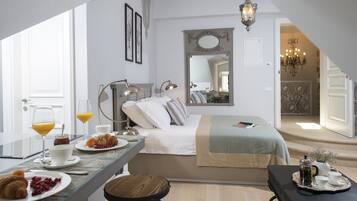 Ein modernes Hotelzimmer mit Bett, Nachttisch, Frühstücksecke und Blick auf den Speisesaal.