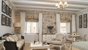 Une pièce chaleureuse avec un mur en pierre, un canapé, une table basse, un fauteuil et un lit.