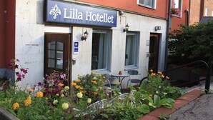 A hotel named Lilla Hotellet with a sign above the entrance, a small outdoor seating area with chairs, and a flower garden in front. - Lilla Hotellet (Eskilstuna)