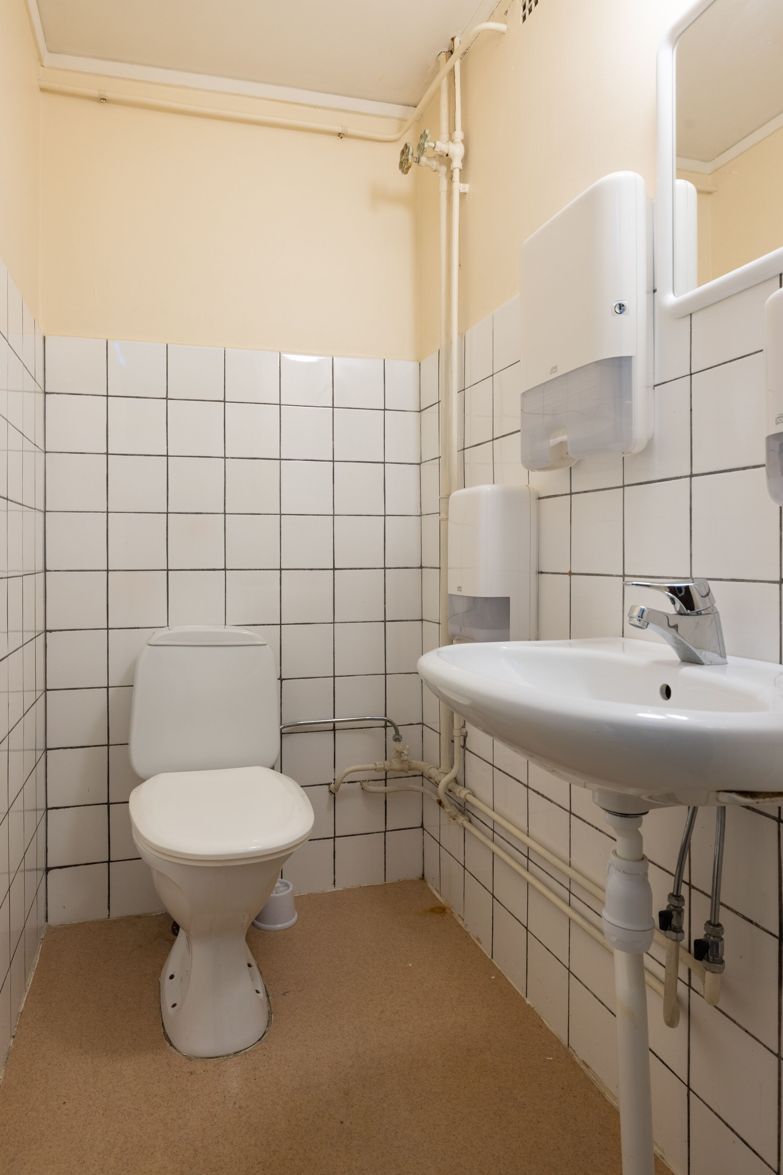 Et badeværelse med toilet, vask og fliserede vægge.