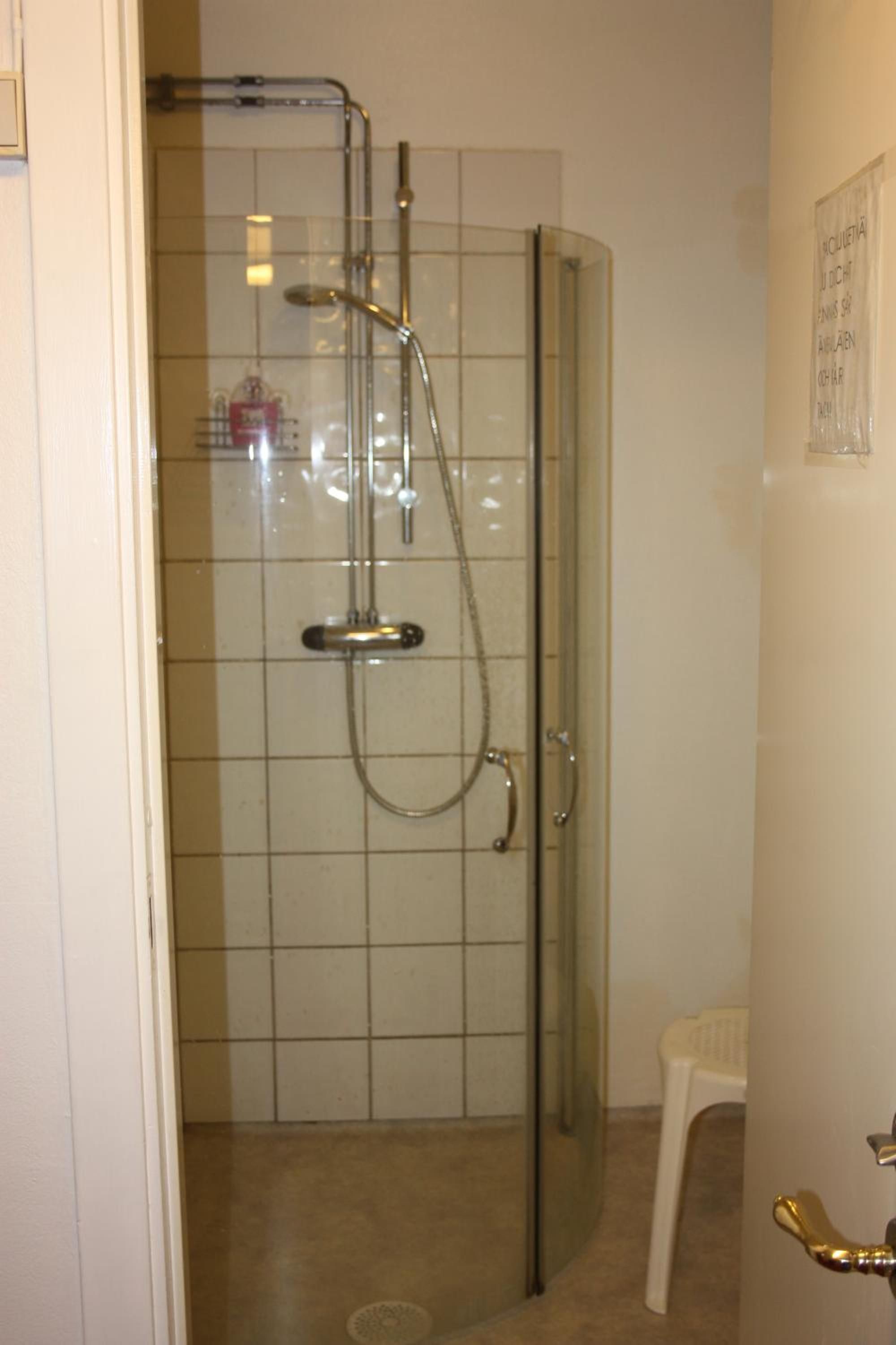 Ducha envuelta en vidrio con un cabezal de ducha de mano y uno fijo en el techo.