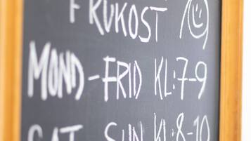 A chalkboard with breakfast hours listed for a week.