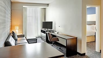 A hotel room with a bed, a desk, a chair, a television, and a window with curtains.