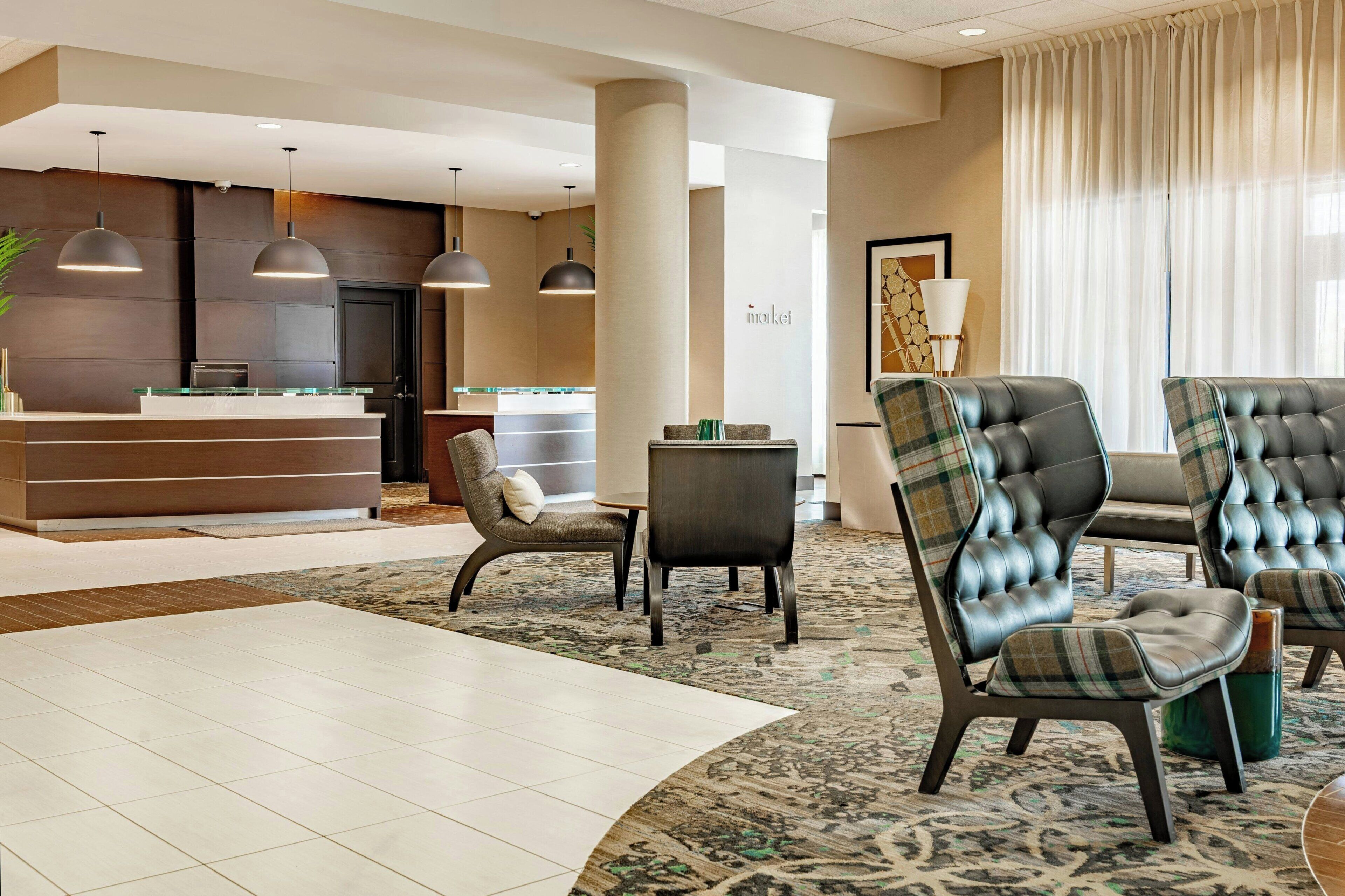 A hotel lobby with a reception desk, seating area, and a patterned carpet.