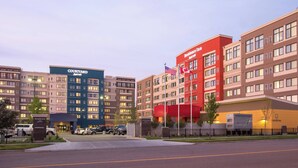 Ett Courtyard by Marriott-hotell med flera byggnader, en flagga och en pendelbusservice.