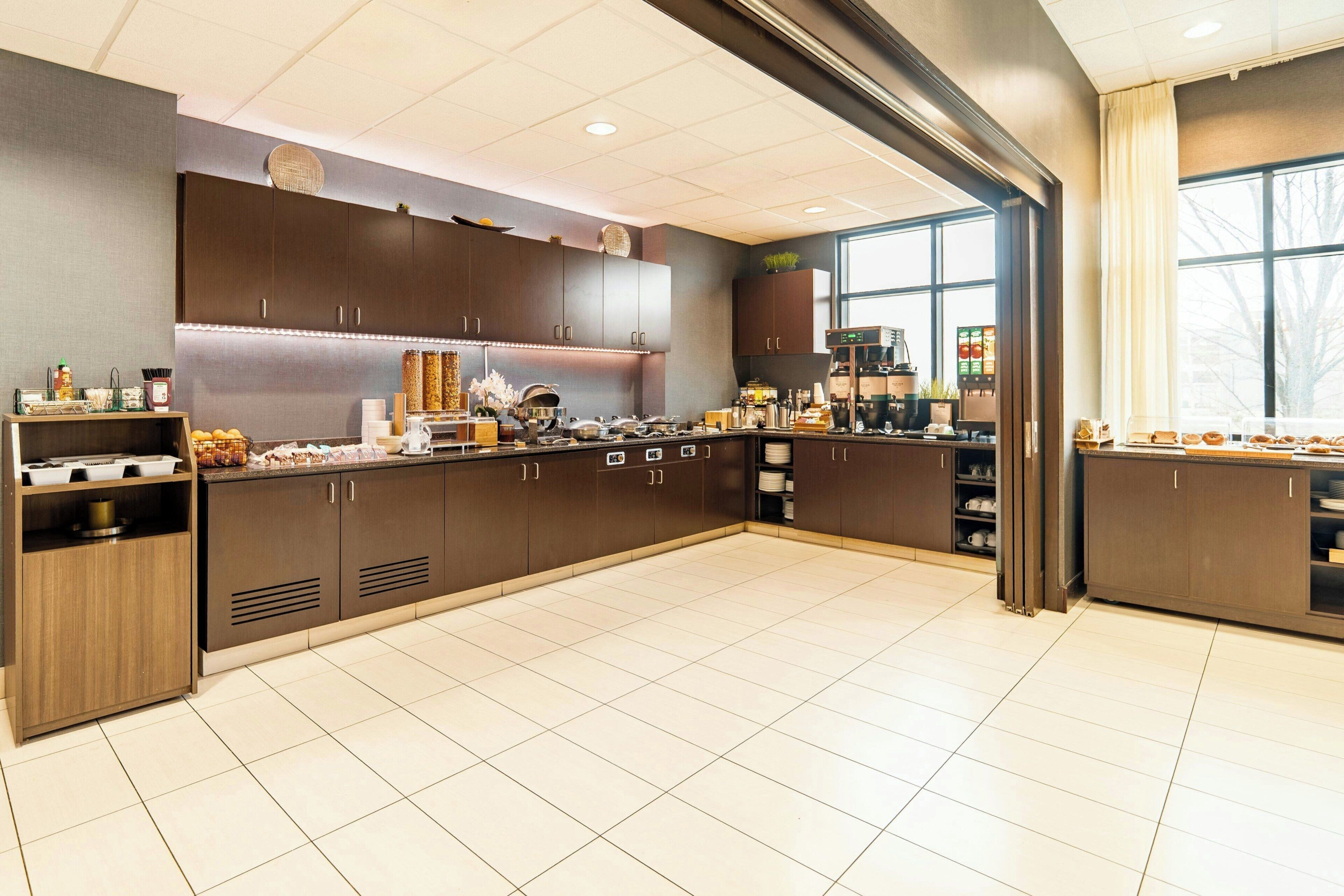 A modern kitchen with dark wood cabinets, a coffee machine, and a large window.