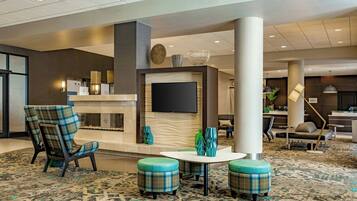A lobby with a reception desk, a fireplace, seating area, and a television.