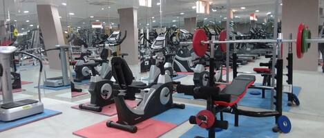 Ein Fitnessstudio mit verschiedenen Trainingsgeräten, darunter Laufbänder, Ergometer und Kraftgeräte.
