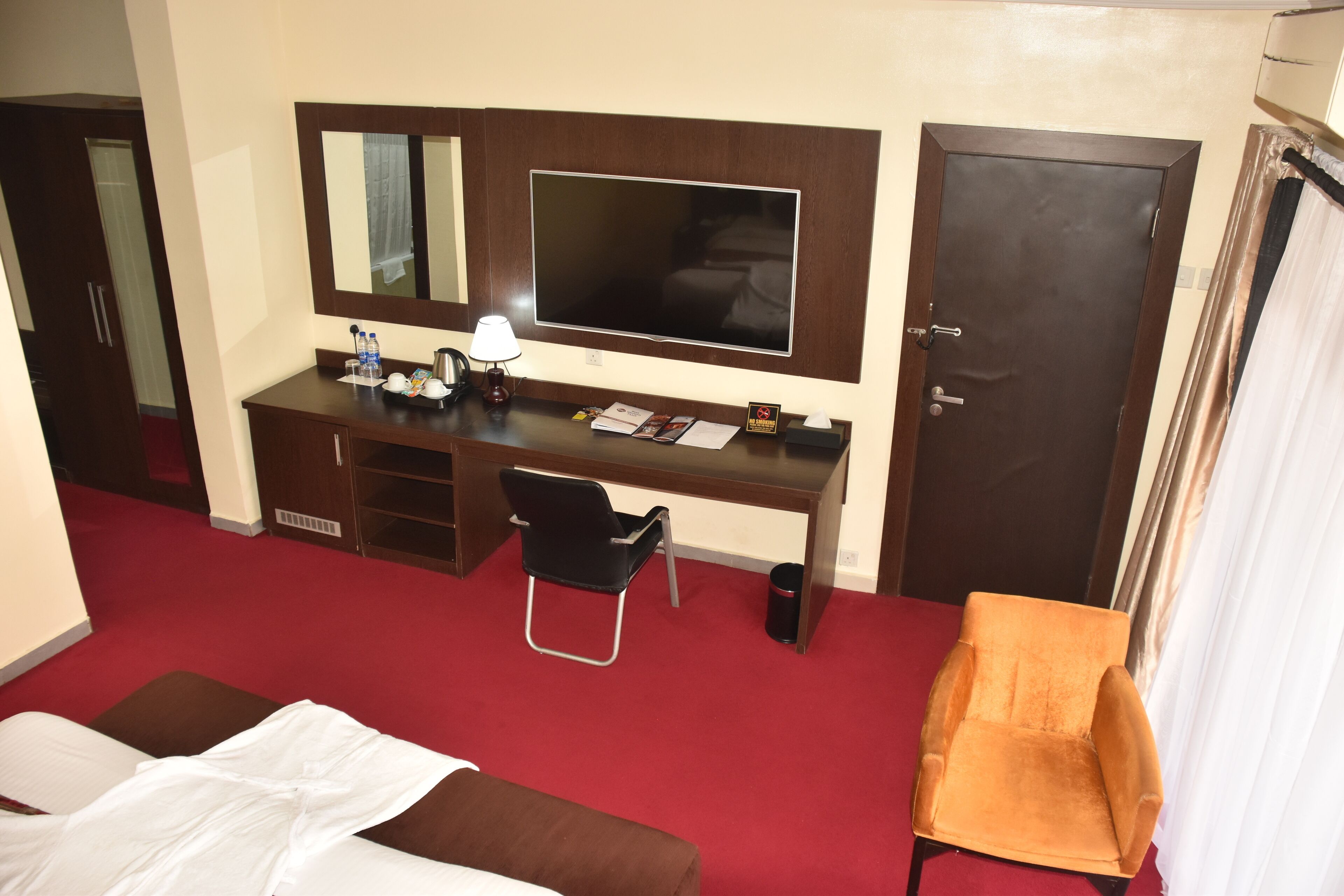 Ein Hotelzimmer mit Bett, Schreibtisch mit Computer, Stuhl, Fernseher und Kleiderschrank.