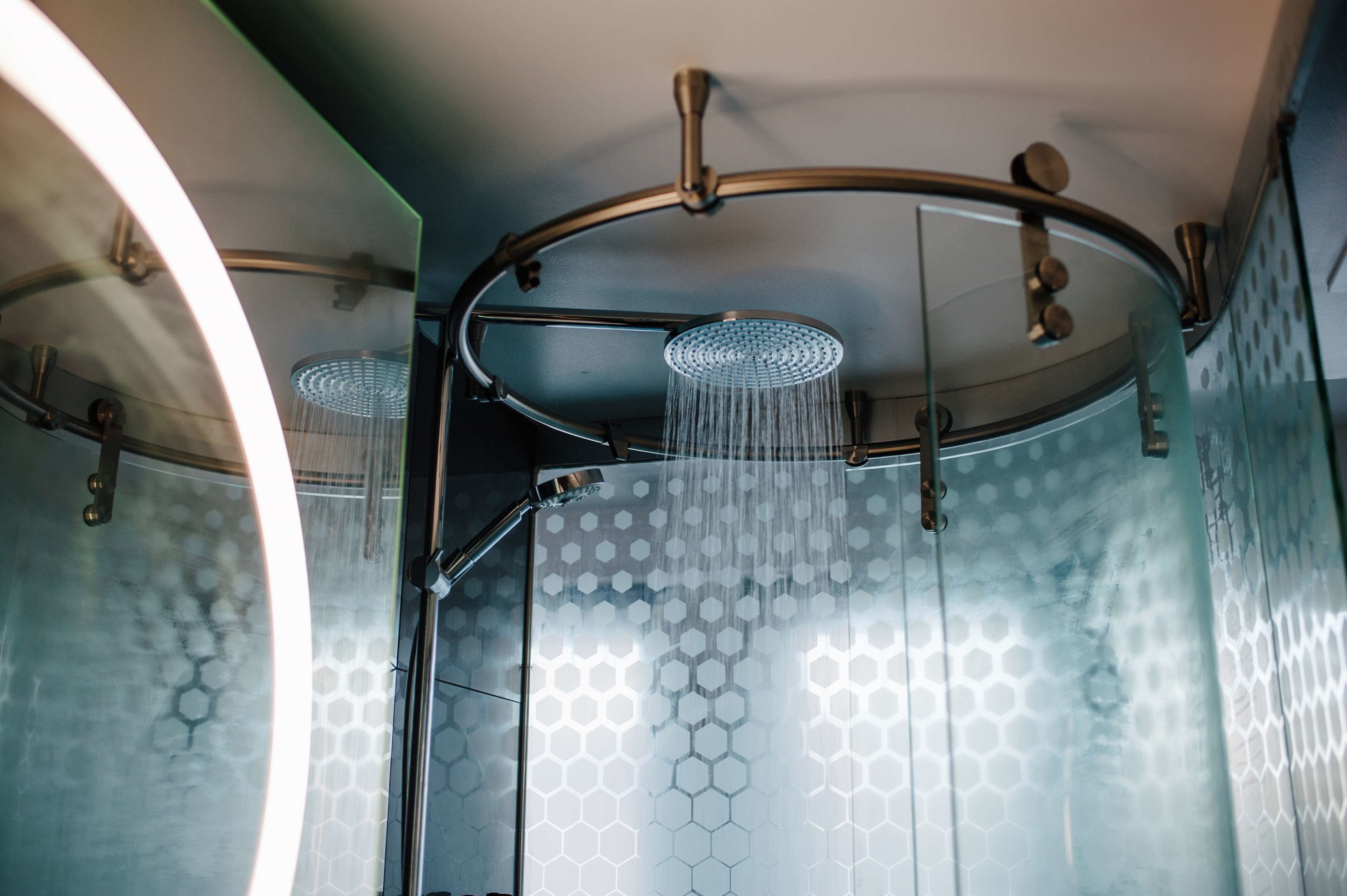 A modern shower with a curved glass enclosure and a hexagonal pattern on the walls.