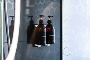 Un baño con separador de vidrio y un patrón de baldosas hexagonales en la pared.