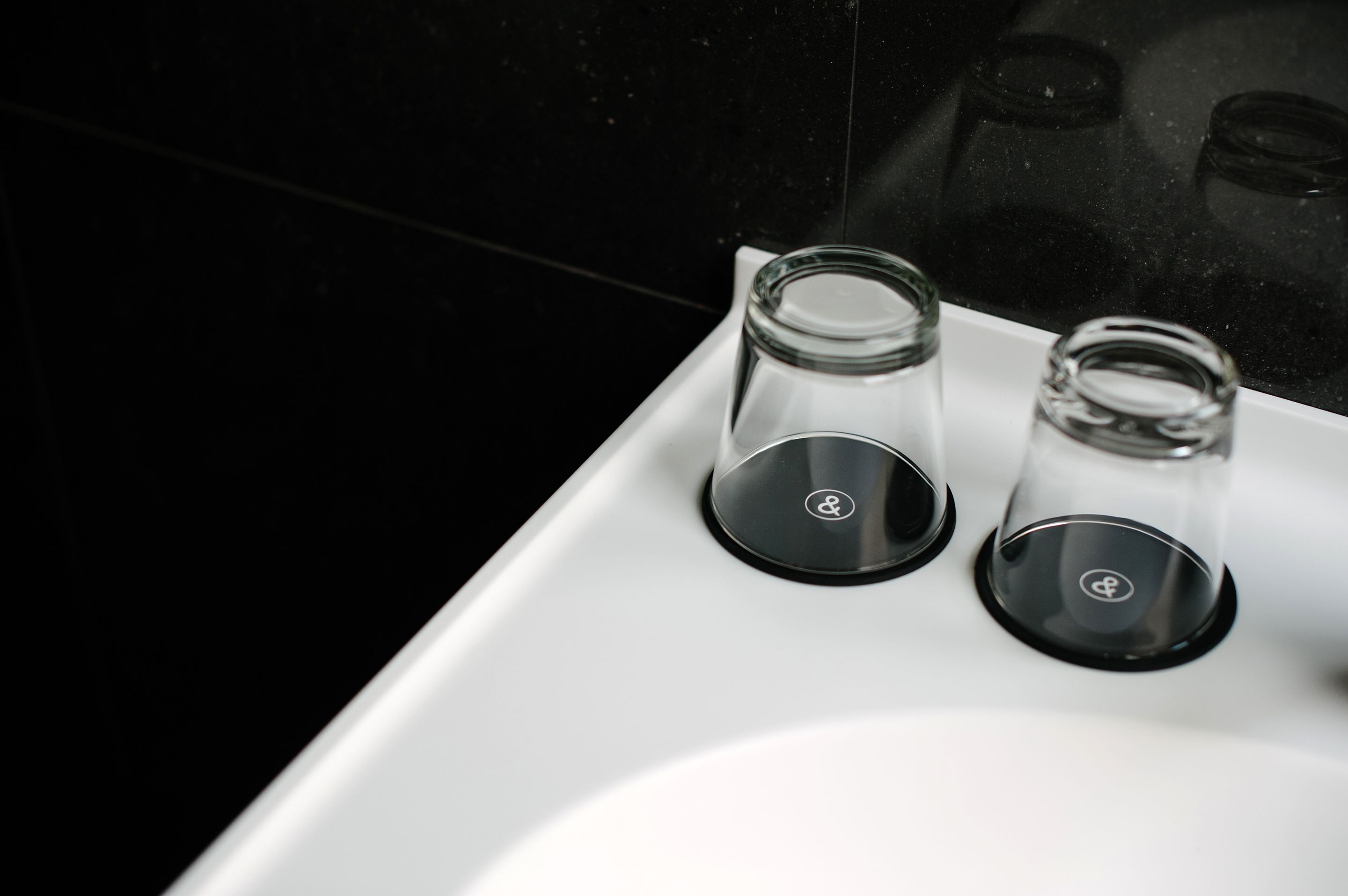 A bathroom sink with two glass containers on the countertop.