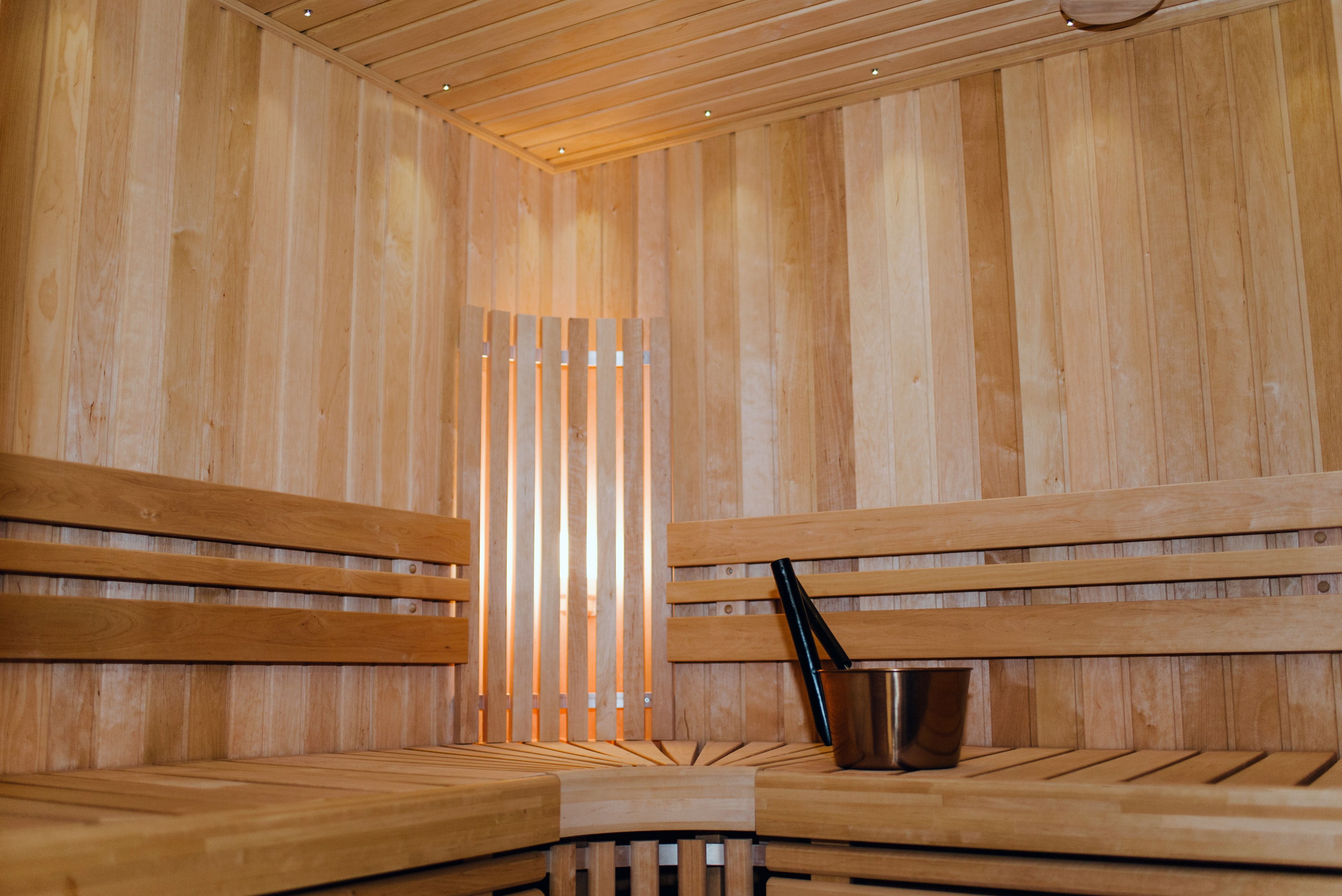 Una sauna de madera con bancos y un cubo de metal.
