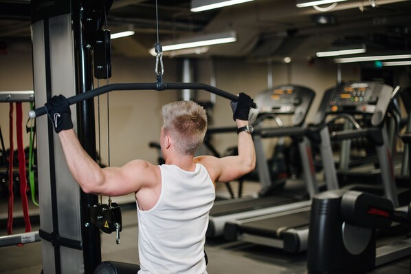 A gym with exercise equipment, treadmills, and a person using a cable machine. - Best Western and hotel (Stockholm)