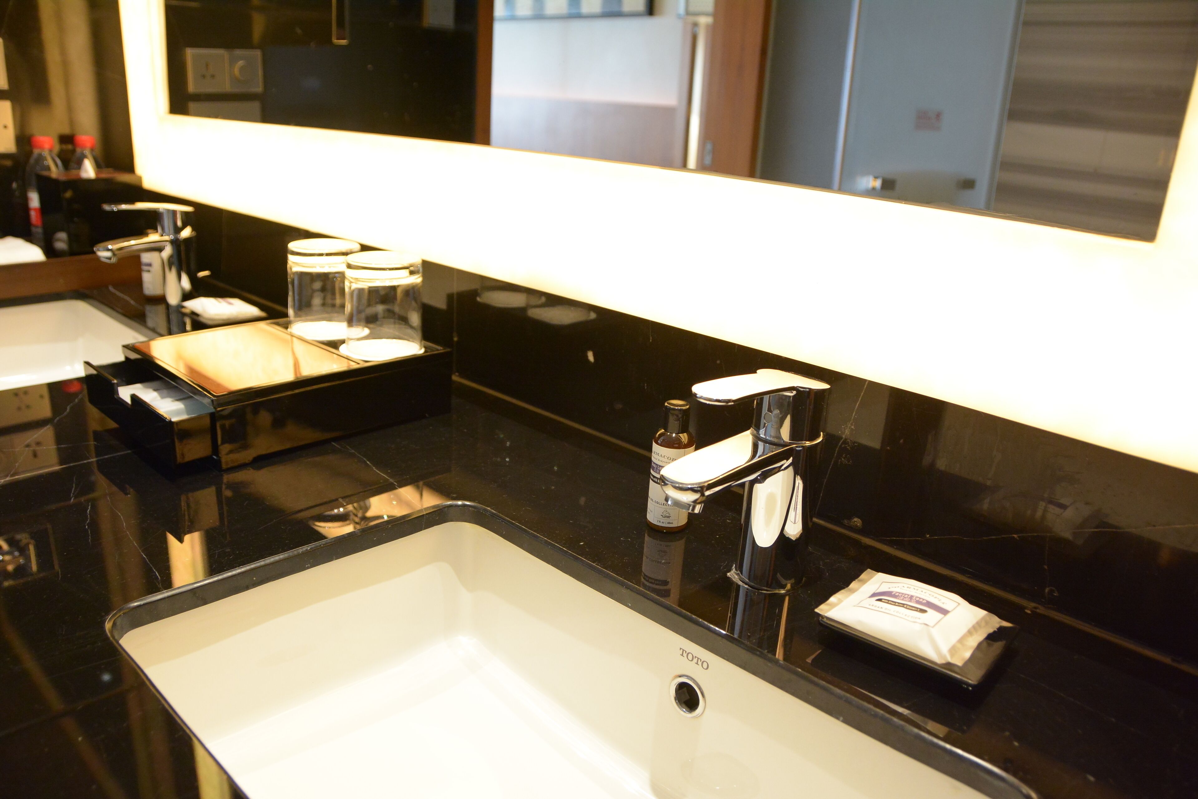 Un baño moderno con encimera negra, lavabo blanco y espejo encima.