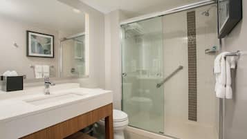 A modern bathroom with a glass-enclosed shower, a white sink, and a toilet.