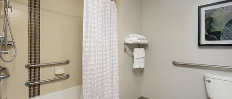 A bathroom with a bathtub, shower, toilet, and a towel rack with towels.