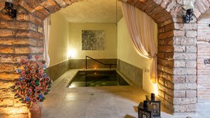 A spa area with a stone floor, a hot tub, and a decorative tree sculpture.