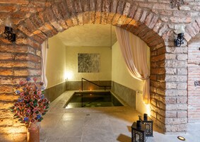 Un área de spa con suelo de piedra, un jacuzzi y una escultura de árbol decorativa.