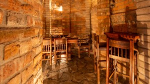 A rustic room with exposed brick walls, stone flooring, wooden furniture, and a brick ceiling.